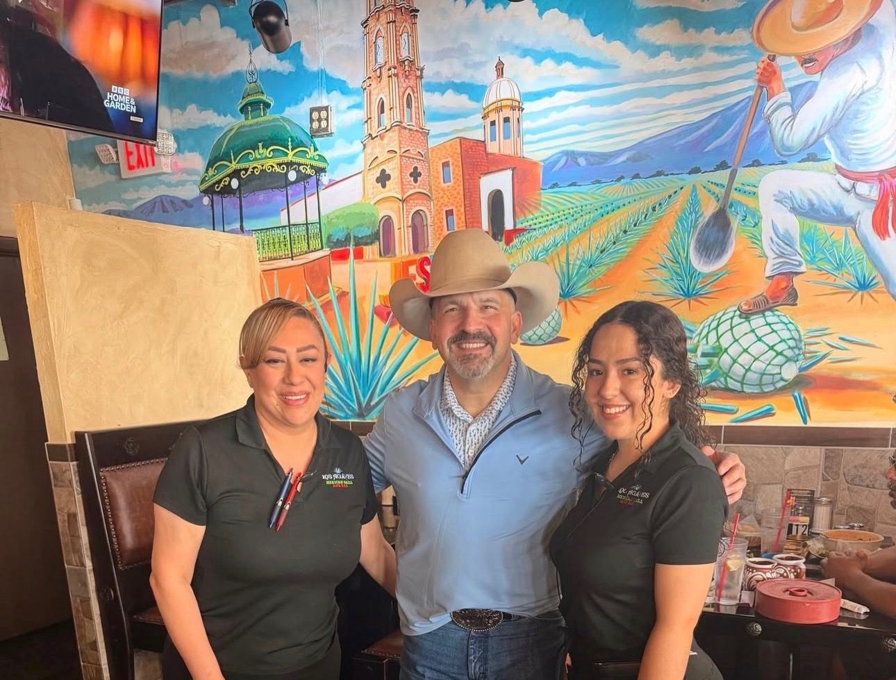 The Los Agaves family smiling in front of the hand-painted agave mural